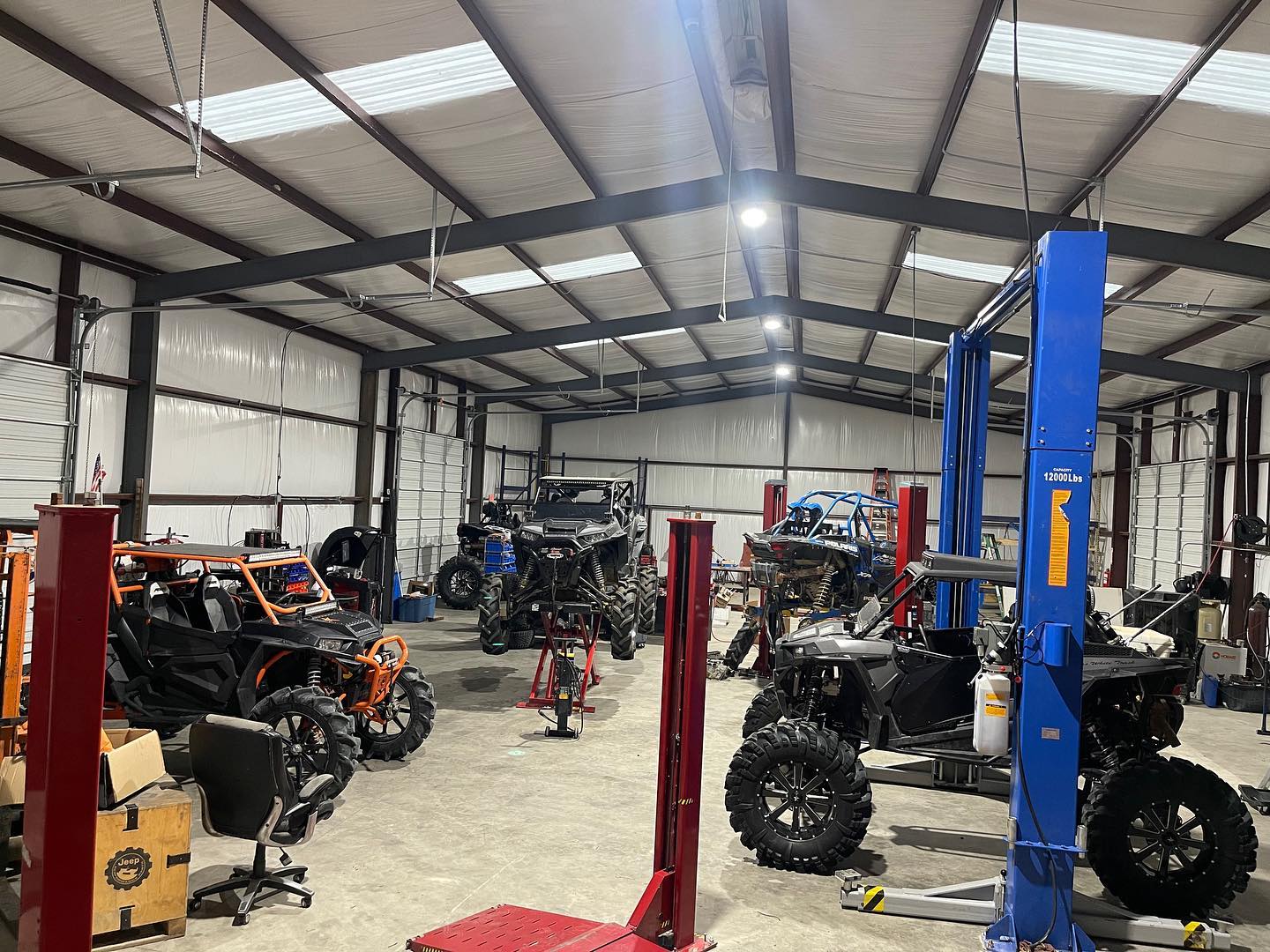Professional ATV/UTV repair shop with multiple vehicles on lifts in clean, well-equipped service facility
