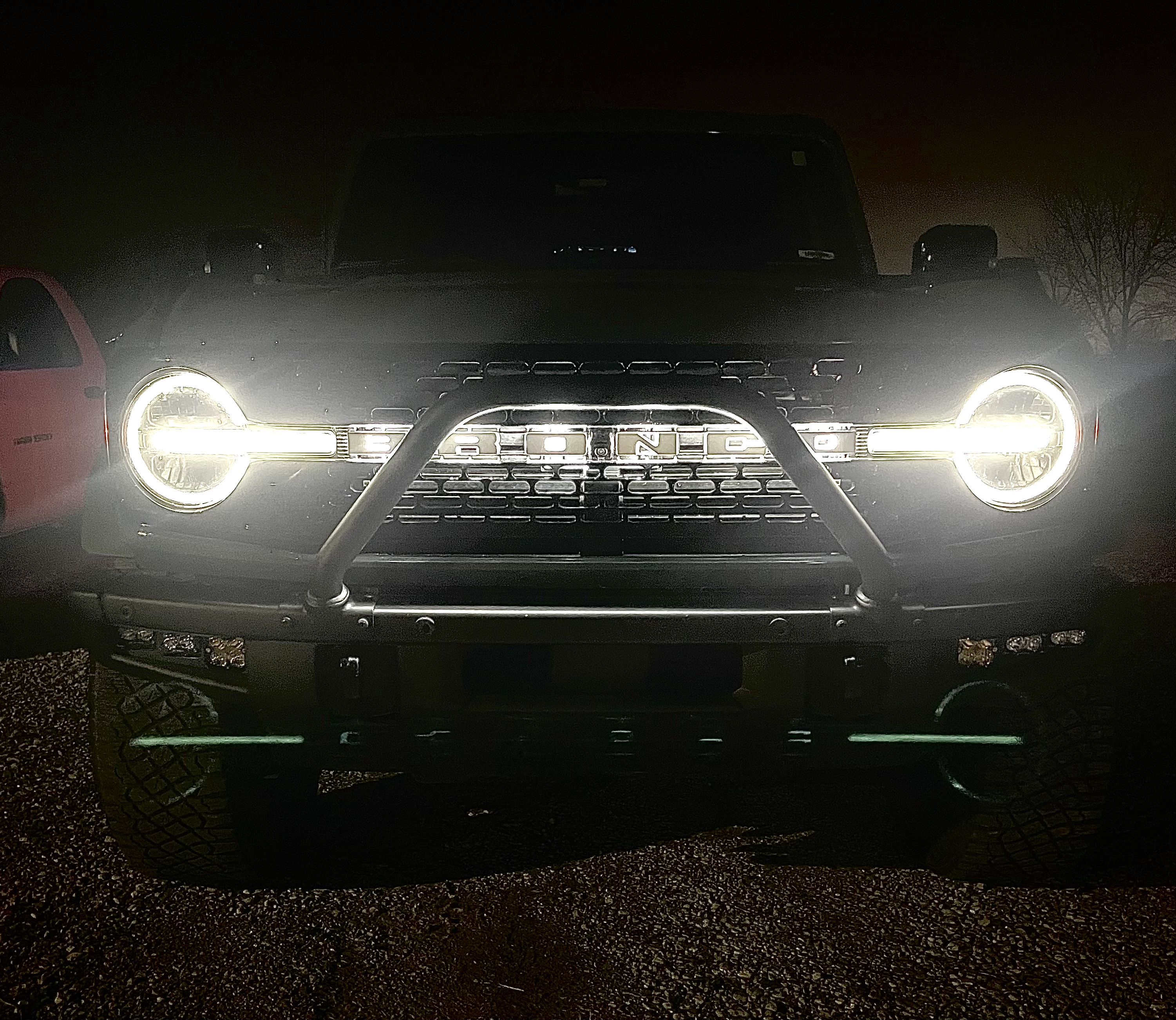 Ford Bronco with custom bumper and LED headlights illuminated at night