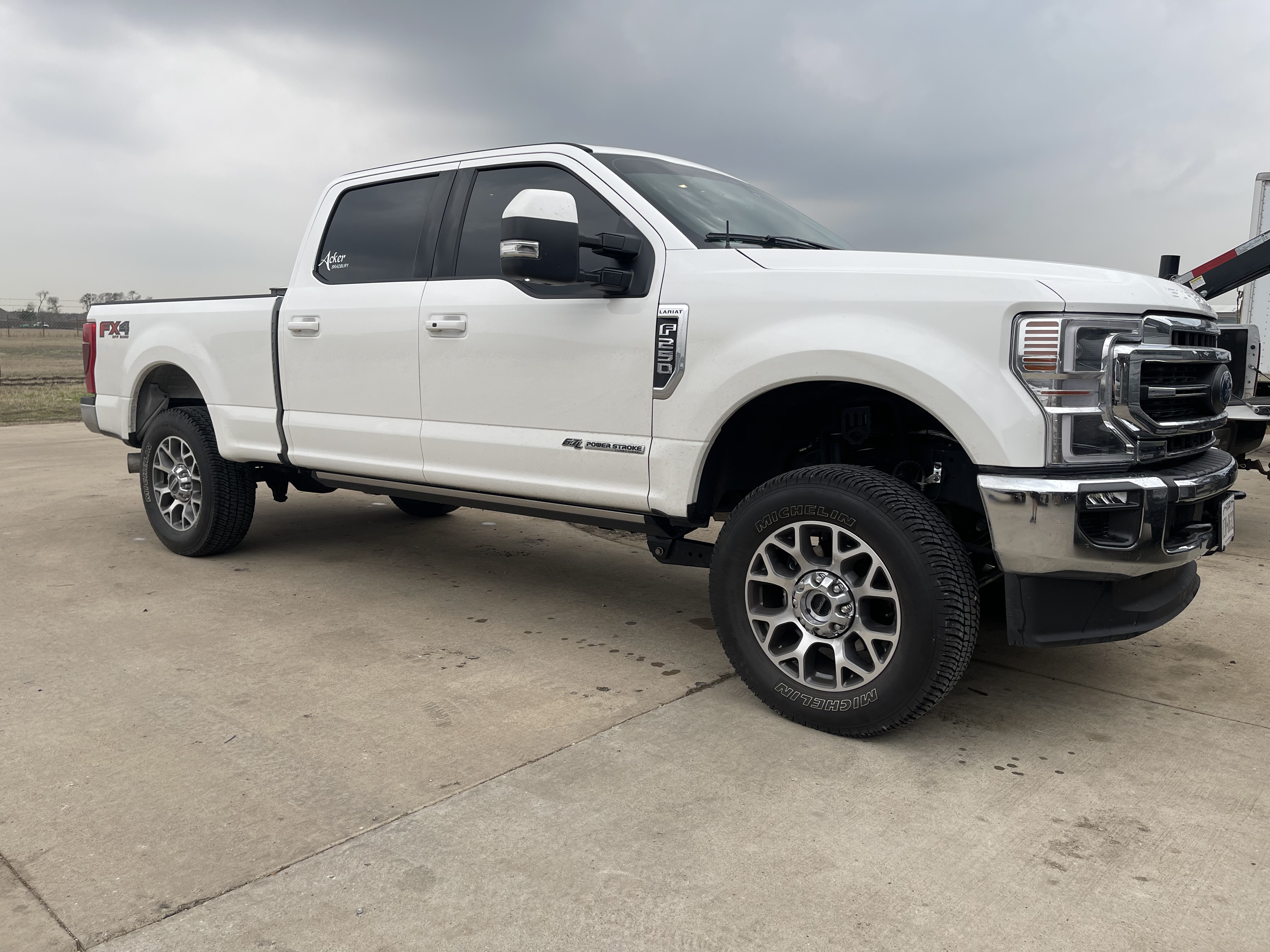 Lifted white Ford F-250 with custom wheels and chrome bumper